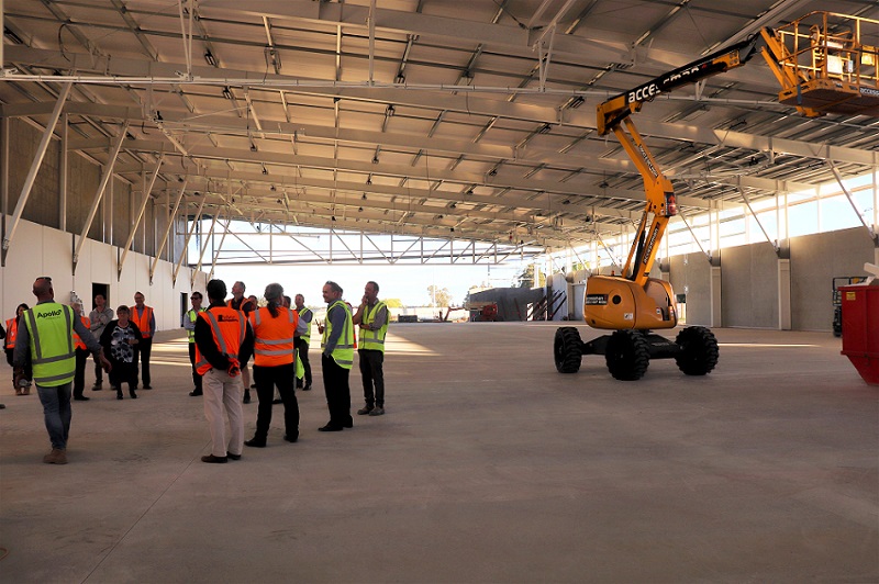A group of people in high visibility jackets take a tour of the indoor courts