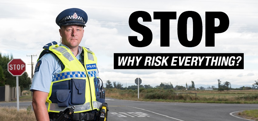 A policeman standing at an intersection with a stop sign visible behind him and a caption that say STOP why risk everything?