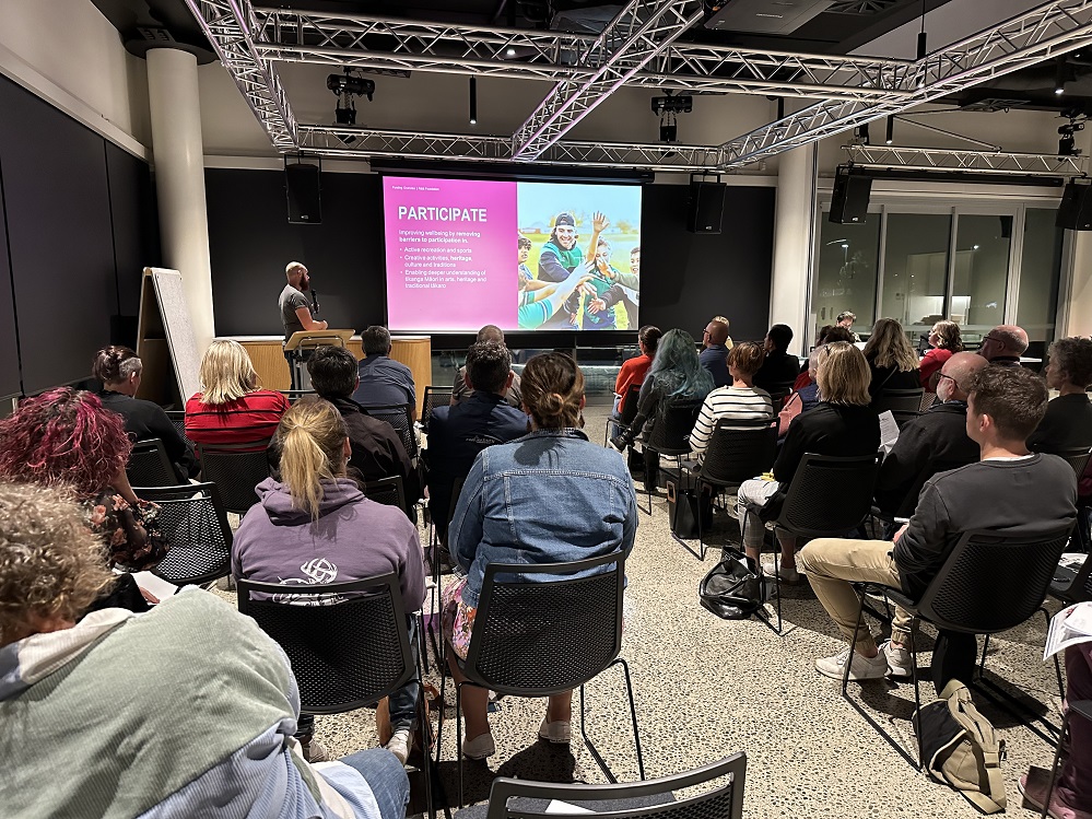 A room of people watching a presentation