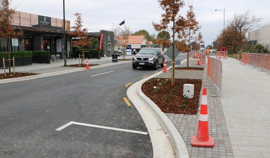 A black car drives down the newly reopened section of Tennyson Street, between the wider pedestrian walkways