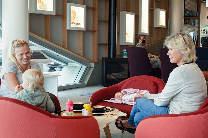 A mum, grandmother and baby sitting at the cafe in Te Ara Ātea