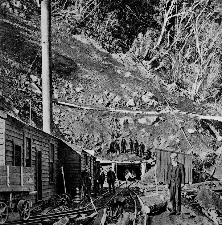 Historic black and white image of workers digging the Ōtira tunnel with men standing on the tracks and on the hillside above the tunnel