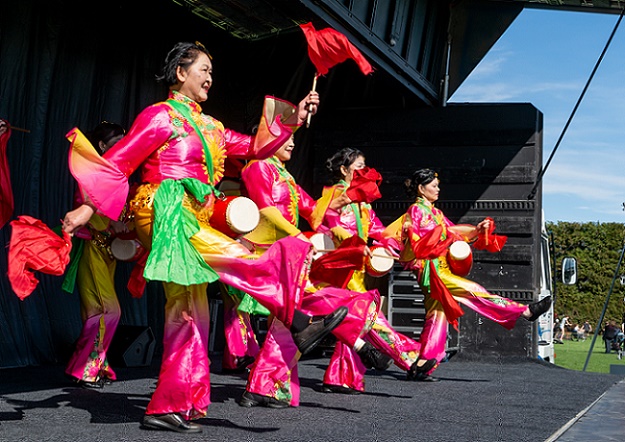 A group of women in brightly coloured traditional Chinese dress dance on the stage at CultureFest