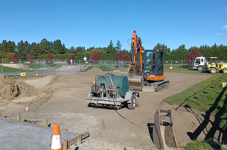 a bulldozer and trailer in the foreground of a worksite