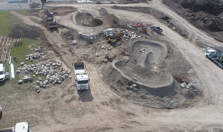 aerial image of a work site with a pear shaped contour of mounded dirt next to a bowl shaped hole 
