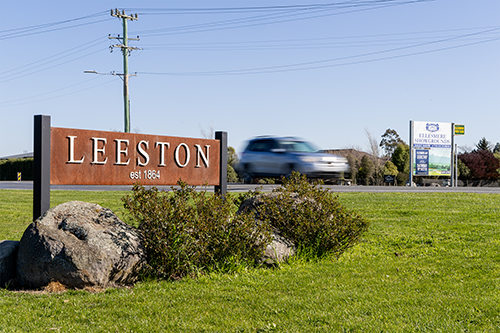 Leeston sign with car driving past in background