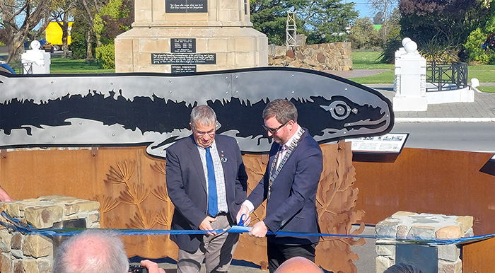 Mayor Sam and community man cut rope in front of eel sculpture