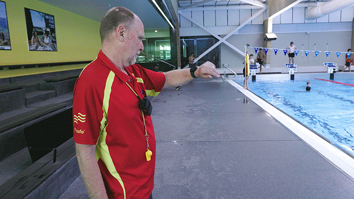 lifeguard at swimming pool checks his watch with the AI technology on it