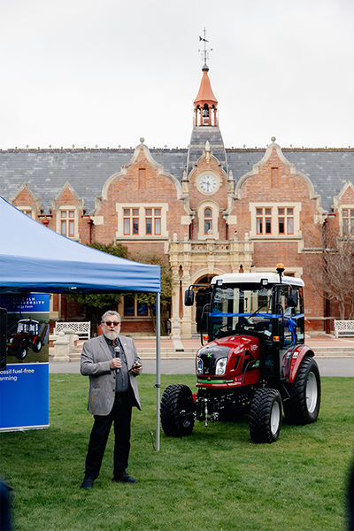 Man standing with microphone next to electric tractor 
