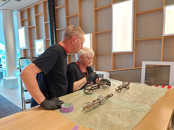 A  woman and a man gather around heritage artifact