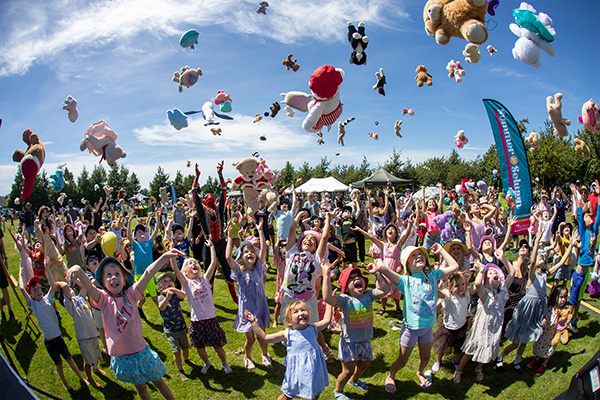 children throwing teddy bears in the sky