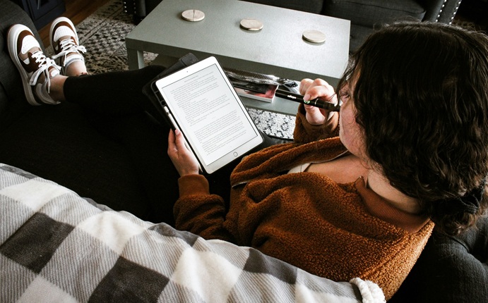 Person lying on a couch reading an ebook on a tablet