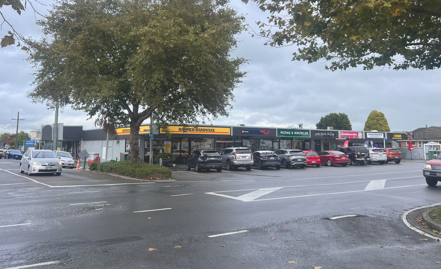 Photo of street with cars parked outside businesses