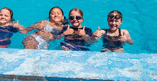Three children posing for a photo in a swimming pool
