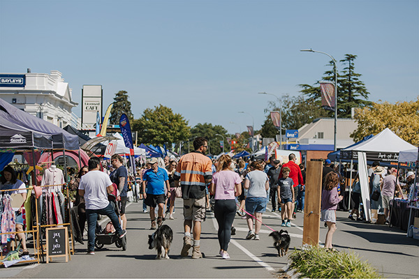 A crowd of people walk down the main street in Leeson surrounded by stalls
