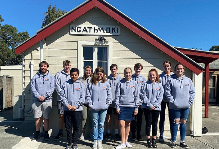 The Youth Council in grey hoodies standing in front of a building at Ngati Moki marae