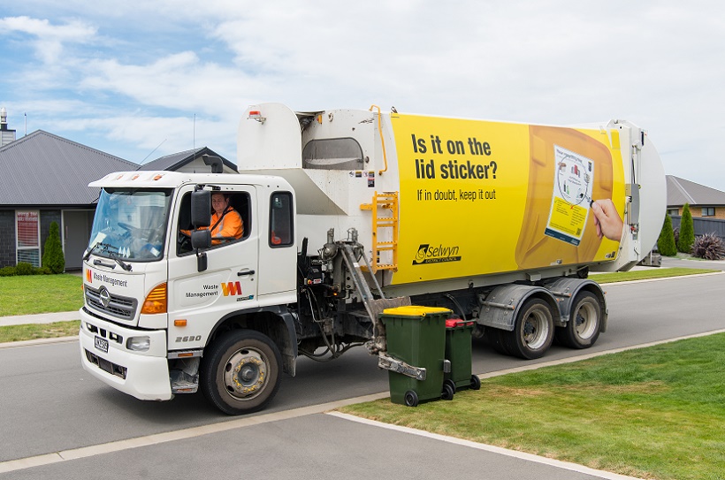 A recycling truck picking up a yellow recycling bin from the kerbside