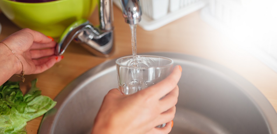 water poured into glass in sink
