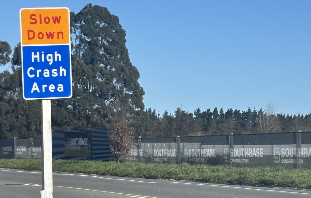 Close up of a sign saying slow down, high crash area