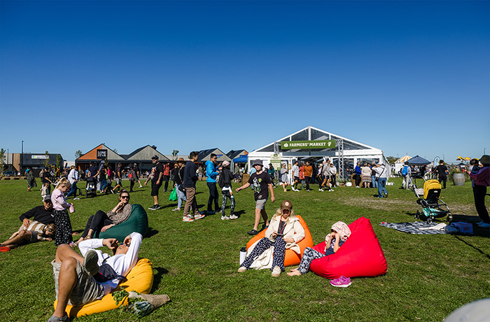 A crowd of people sit and gather at the Harvest Festival outside in Rolleston on a sunny day