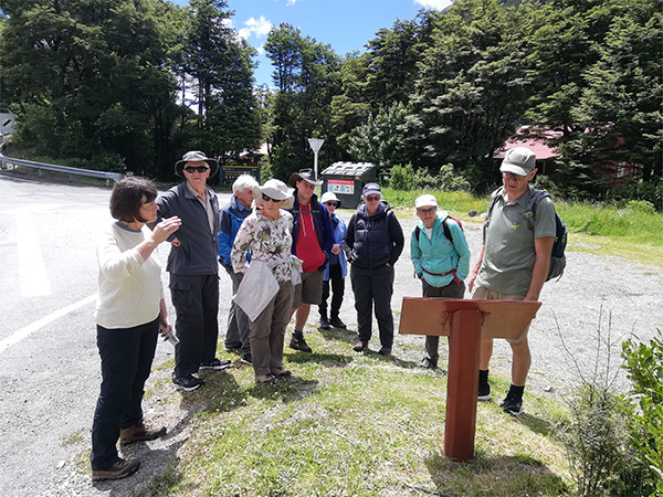 Several people gather around a sign out on a walk in Arthur's Pass