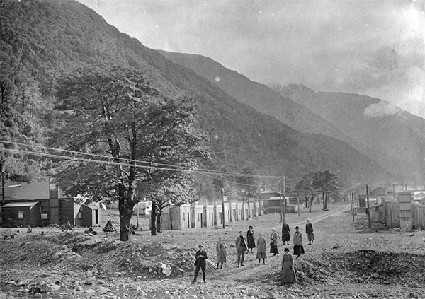 Black and white photo of several people walking up and down street in Arthur's Pass from 1914