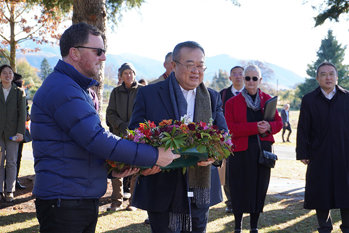 Visitors stand with floral wreath