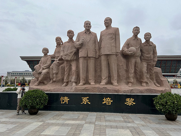 Woman stands next to statues in China