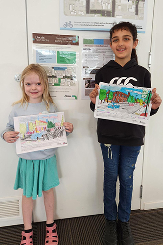 Children holding up winning colouring competition entries