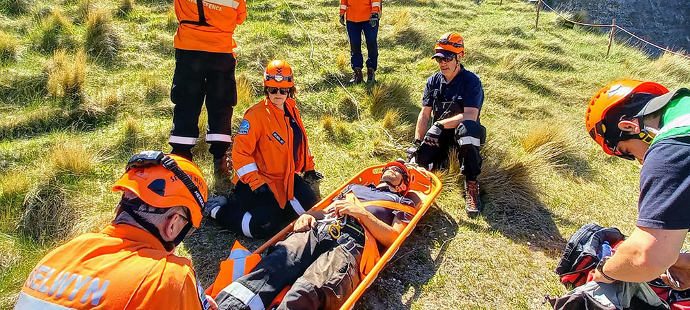 people in high visibility gear and hard hats loading a patient onto a stretcher