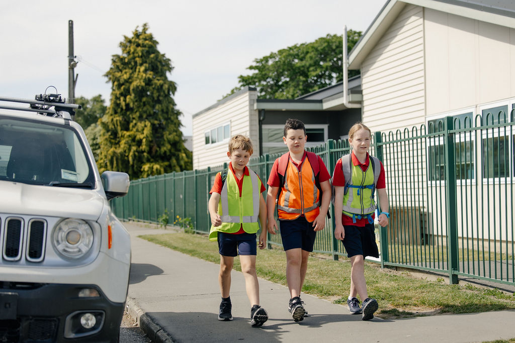 Children walking outside a school wearing hi-vis clothing