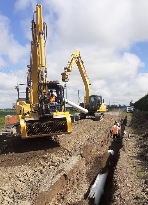Two diggers working next to a trench with a pipeline in it